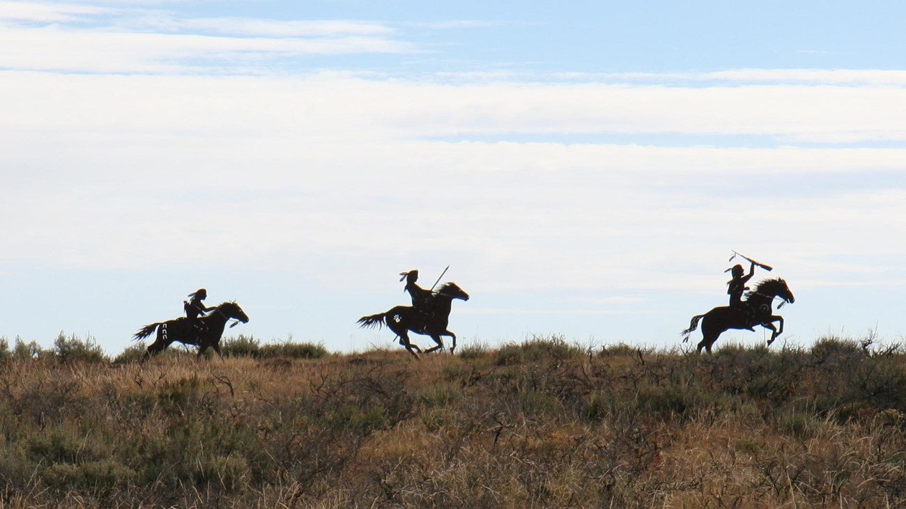 Three silhouettes of Nez Perce warriors on horseback.